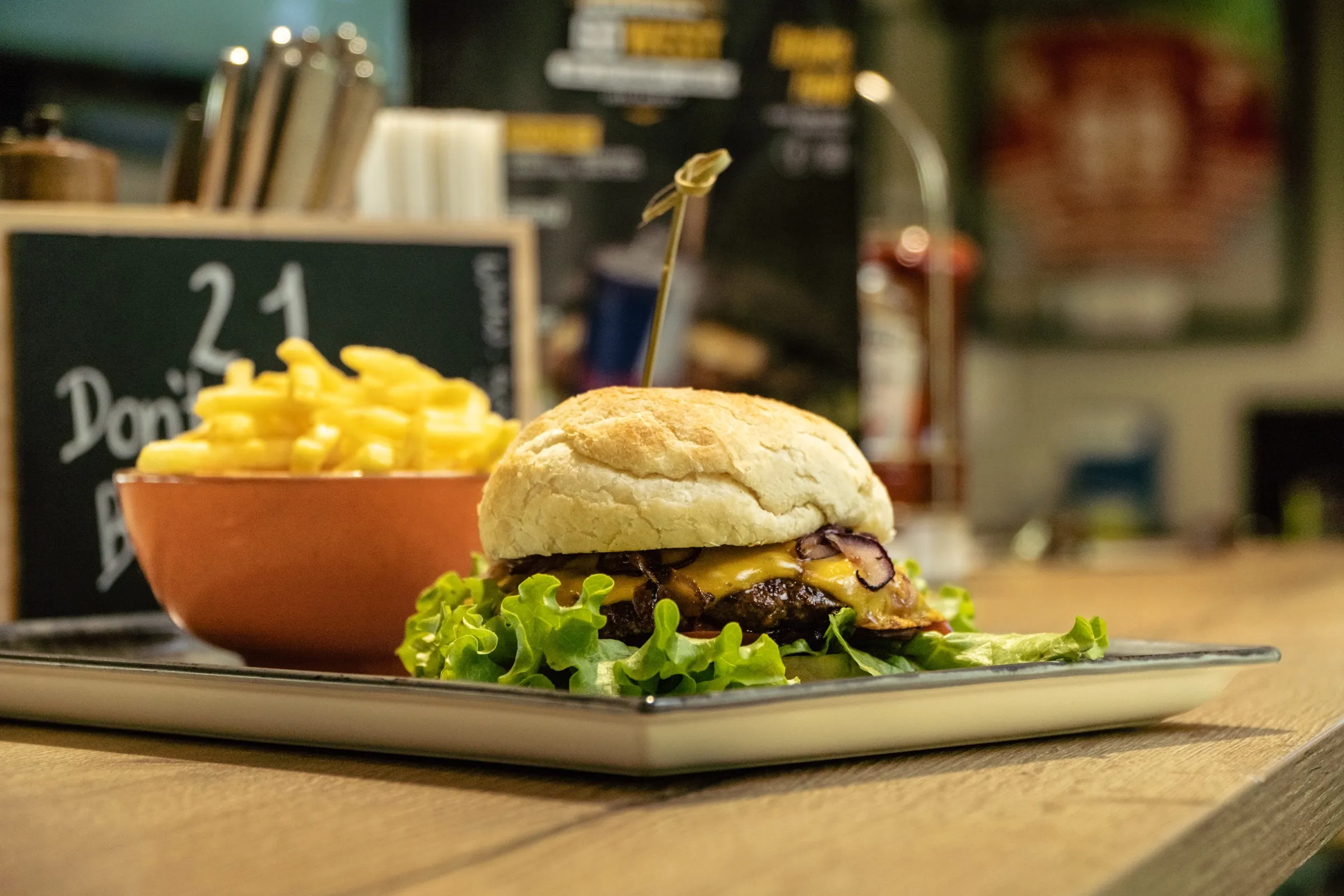 Burger mit Pommes auf einem Holztisch in einem Restaurant