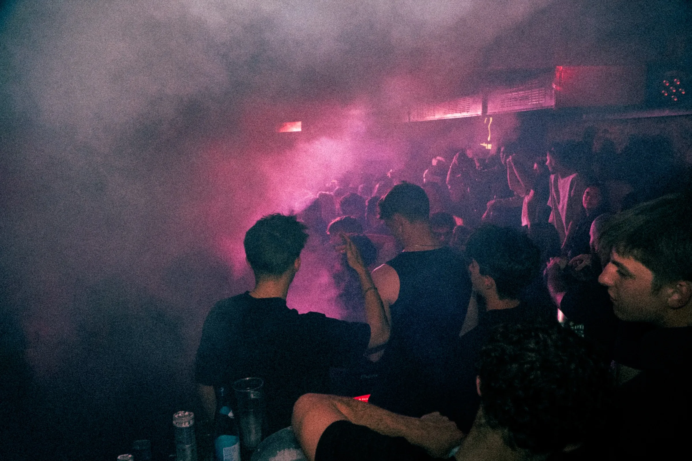 Tanzende Menschen in pinkem Licht und Nebel bei einer Clubnacht